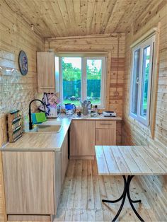 a kitchen with wooden walls and flooring next to a table in front of a window