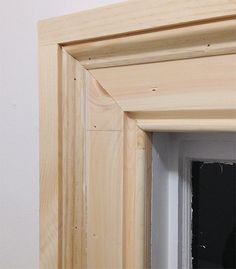 an open window with wood trim on the outside and inside walls, in front of a white wall