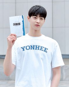 a young man holding up a piece of paper with the word yonhee on it