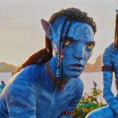 two people dressed as avatars with blue paint on their faces and hair, one is staring at the camera