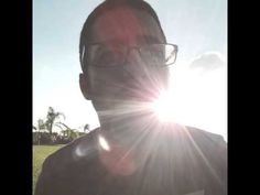 the man is wearing glasses and standing in front of the sun