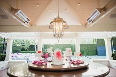 a wedding cake on top of a table in a room with large windows and chandelier