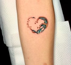 a woman's arm with a heart shaped wave tattoo on it