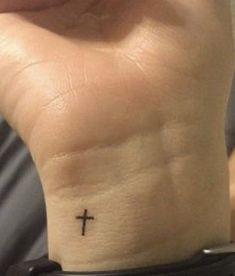 a person with a small cross tattoo on their wrist