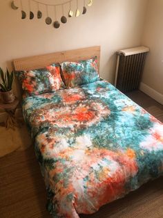 a bed with a colorful comforter on top of it next to a wall mounted heater