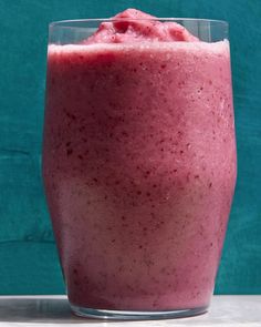 a smoothie in a glass on top of a counter next to a blue wall