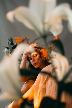 a woman is sitting in front of some flowers