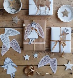 christmas decorations and gifts laid out on a wooden table with paper angel cutouts, star garlands, and other items