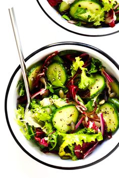 two white bowls filled with salad on top of a table