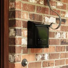 a black mailbox mounted to the side of a brick wall next to a door