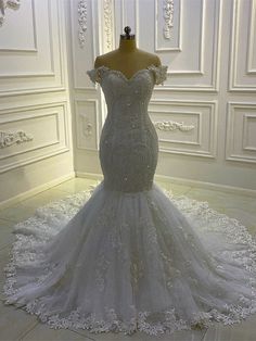 a white wedding dress on display in a room with white walls and flooring,