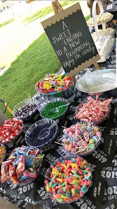 a table full of candy and candies for sale at an outdoor event with a chalkboard sign