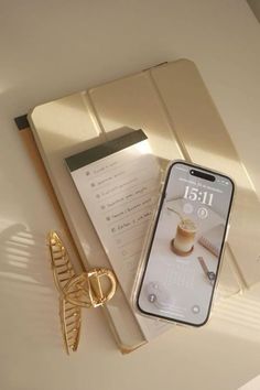 a cell phone sitting on top of a table next to a pair of gold scissors