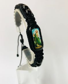 "Pulsera de San Judas Tadeo hecha a mano de doble tejido estilo Macrame con hilo reforzado en color negro. San Judas Tadeo el patrono de caso imposible. Pulsera ajustable y expandible para hombre o mujer con minimo cierre de 7\" pulgadas hasta maximo de 9\" pulgadas. Tableta de madera (1\"x 1/2\" x 1/4\" ) color verde obscuro con imagen de alta definicion San Judas en ambos lados y cubierta con resina Hilo reforzado #18 color Negro Bolas gemstone Onyx negro 8mm Nudo: 12" Adjustable Black Woven Friendship Bracelets, Casual Black Woven Friendship Bracelets, Artisan Hand Wrapped Black Bracelets, Artisan Hand Wrapped Black Bracelet, Artisan Hand-wrapped Black Bracelet, Black Woven Bracelet Gift, Black Woven Braided Bracelets For Gift, Black Woven Braided Bracelets As Gift, Black Woven Braided Bracelet For Gifts