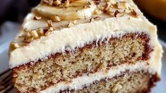 a slice of cake with white frosting and nuts on top