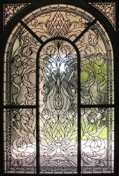 an ornate stained glass window with flowers and leaves on it's side, in front of