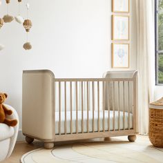 a baby crib with a teddy bear sitting on the floor in front of it