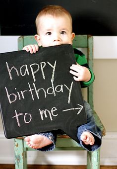 a young boy holding up a chalkboard that says happy birthday to me