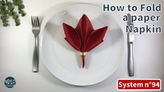 a white plate topped with a red napkin next to a fork and knife on top of it