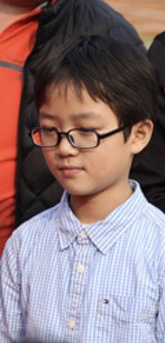 a young boy wearing glasses looking at his cell phone