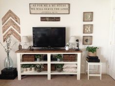 a living room with a tv and some plants on the table in front of it