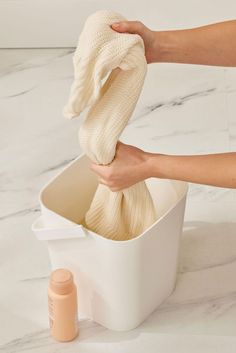 a person holding a cloth in a white container