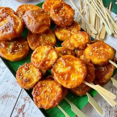 some food is sitting on a green plate with toothpicks in the middle and chopsticks sticking out of it