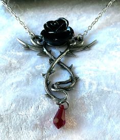 Roses are red, or so the aphorism goes... but not in the mountains of Romania, where the darkest of romances prevail. A drama to your darkest attire! Twisted pewter roses vine encapsulate a jet black rose. The most beautiful blood red, Austrian crystal dropper appears as if a thorn has pierced the skin. The pendant does have extension links. The pendant comes with a velvet gift pouch. Made by Kiss of a red rose with help from Alchemy England 1977. Gothic Rose-colored Jewelry For Gifts, Gothic Red Ruby Jewelry, Gothic Red Necklace With Chain, Red Gothic Heart Pendant Jewelry, Gothic Collectible Pendant Necklace, Rose Vines, Rose Rouge, Rose Pendant, Alchemy