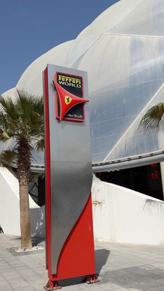 there is a sign that says ferrari world in front of a building with palm trees