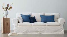 a white couch sitting next to a wooden block with blue and white pillows on it