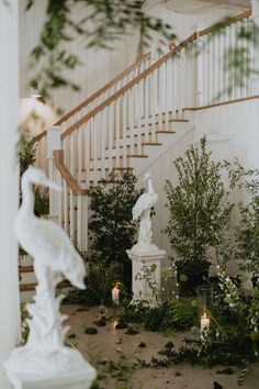 a white statue sitting in the middle of a room next to a staircase and trees