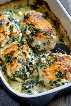 chicken covered in spinach and cheese in a casserole dish with a fork