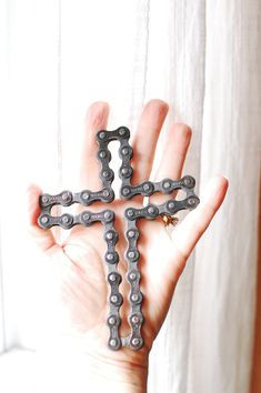 a cross made out of chains held in the palm of someone's left hand