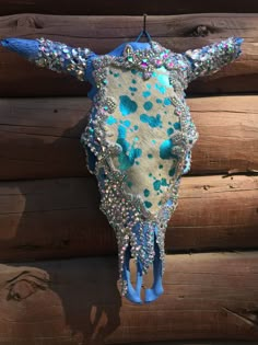 a cow's head hanging on the side of a log wall with blue and green beads