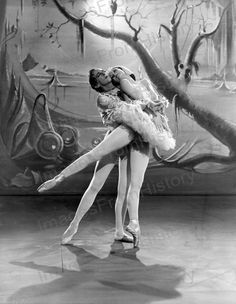 two ballerinas are hugging in front of a backdrop with trees and birds on it