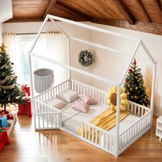 a white dollhouse bed in the middle of a room with christmas trees and presents