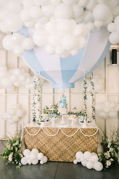 a table topped with white balloons next to a cake