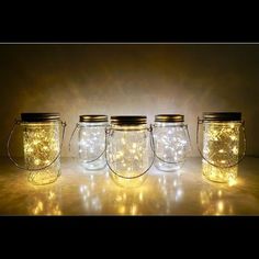 four mason jars with fairy lights in them