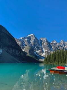 three canoes sitting on the shore of a mountain lake