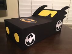 a cardboard box shaped like a batmobile with yellow and black batman logos on it