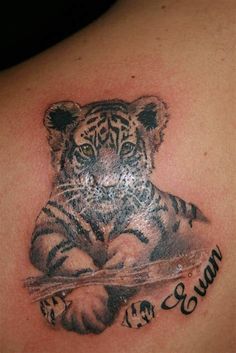 a tiger cub tattoo on the back of a woman's upper arm and shoulder