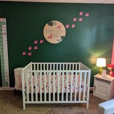 a baby's room with green walls and pink accents