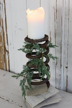 a lit candle sitting on top of a stack of books next to a pine tree