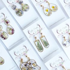 many different types of earrings are displayed on the table with greeting cards in front of them