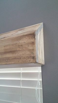 a wooden shelf sitting on top of a window sill next to a gray wall