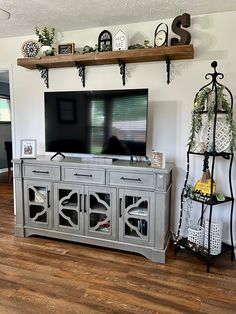 a flat screen tv sitting on top of a wooden entertainment center in a living room