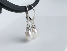 "Gleaming petite white freshwater teardrop pearls wire wrapped in sterling silver and dangling from handcrafted ear wires ( or leverbacks ). Dainty yet sturdy pearl earrings, great for everyday wear as well. ✤ Mad-to-order earrings. Each pair vary slightly. Pearls are approx. 8 x 6mm. - Earrings measure 1\" ( 2.5cm ) with hook ear wires, or 1 & 1/16\" ( 2.7cm ) with leverbacks. - Metal components sterling silver. ✤ Earrings are available in 14k gold filled here: https://www.etsy.com/listing/ White Teardrop Wire Wrapped Pearl Earrings, Adjustable Teardrop Pearl Earrings For Wedding, Delicate Teardrop Wire Wrapped Pearl Earrings, White Wire Wrapped Pearl Earrings For Wedding, Silver Teardrop Wire Wrapped Pearl Earrings, Order Earrings, Teardrop Pearl Earrings, Droplet Earrings, Ear Wires