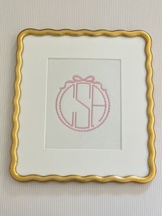 a gold frame with a pink monogrammed elephant on it and a bow in the middle