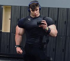 a man with headphones on taking a selfie in front of lockers holding a camera