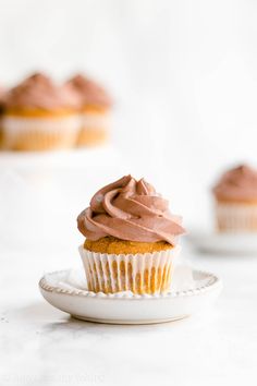 a cupcake with chocolate frosting sitting on a plate next to other cupcakes